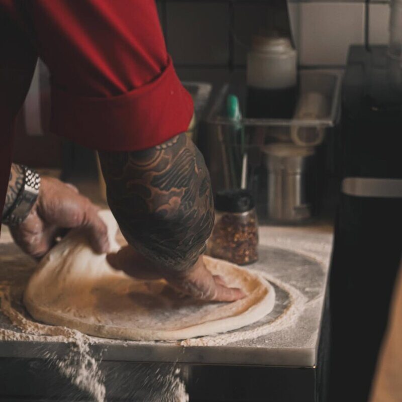 Chef spreading pizza dough by hand at Doughboys kitchen