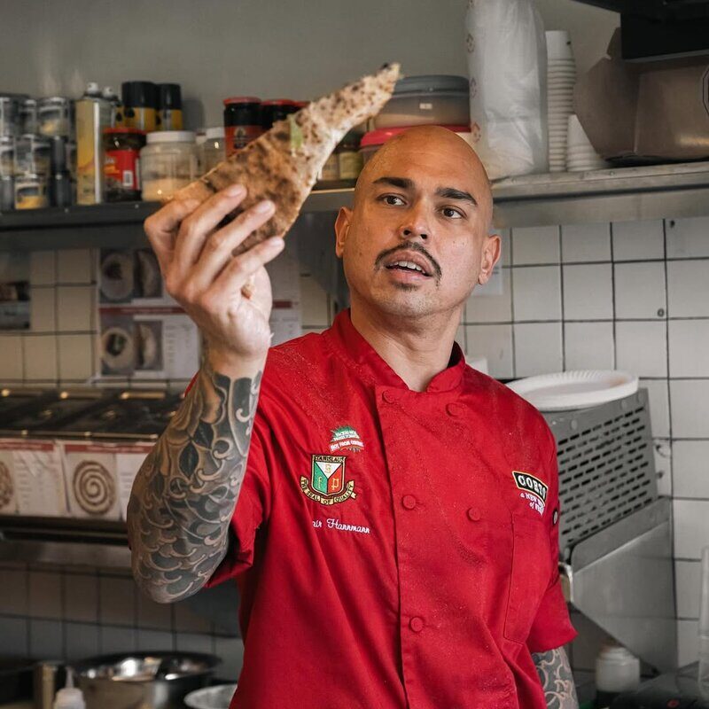 Doughboys chef holding fresh pizza slice in the kitchen