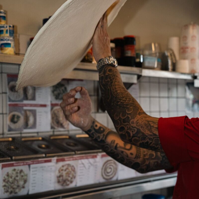 Chef tossing pizza dough in the kitchen at Doughboys Bali